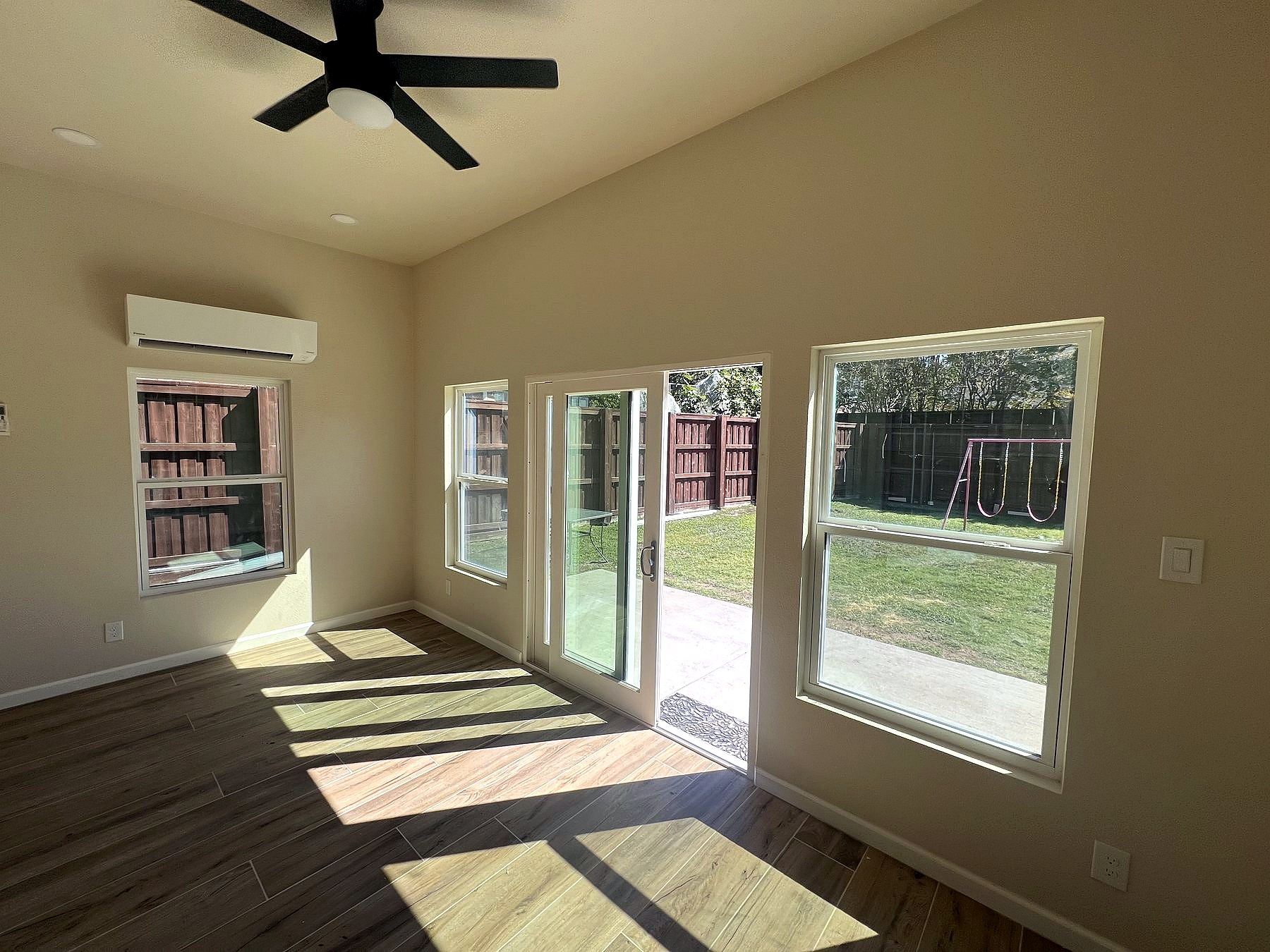 Wide view of the completed sunroom addition with natural light and new flooring